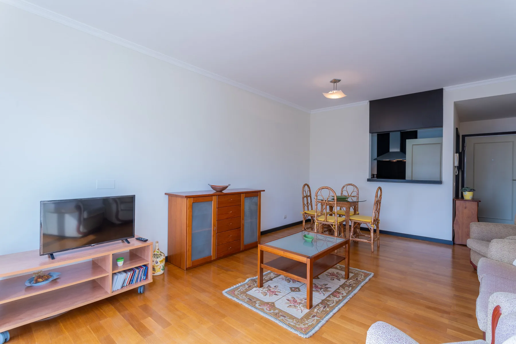 A living room with a television, coffee table, and dining area.