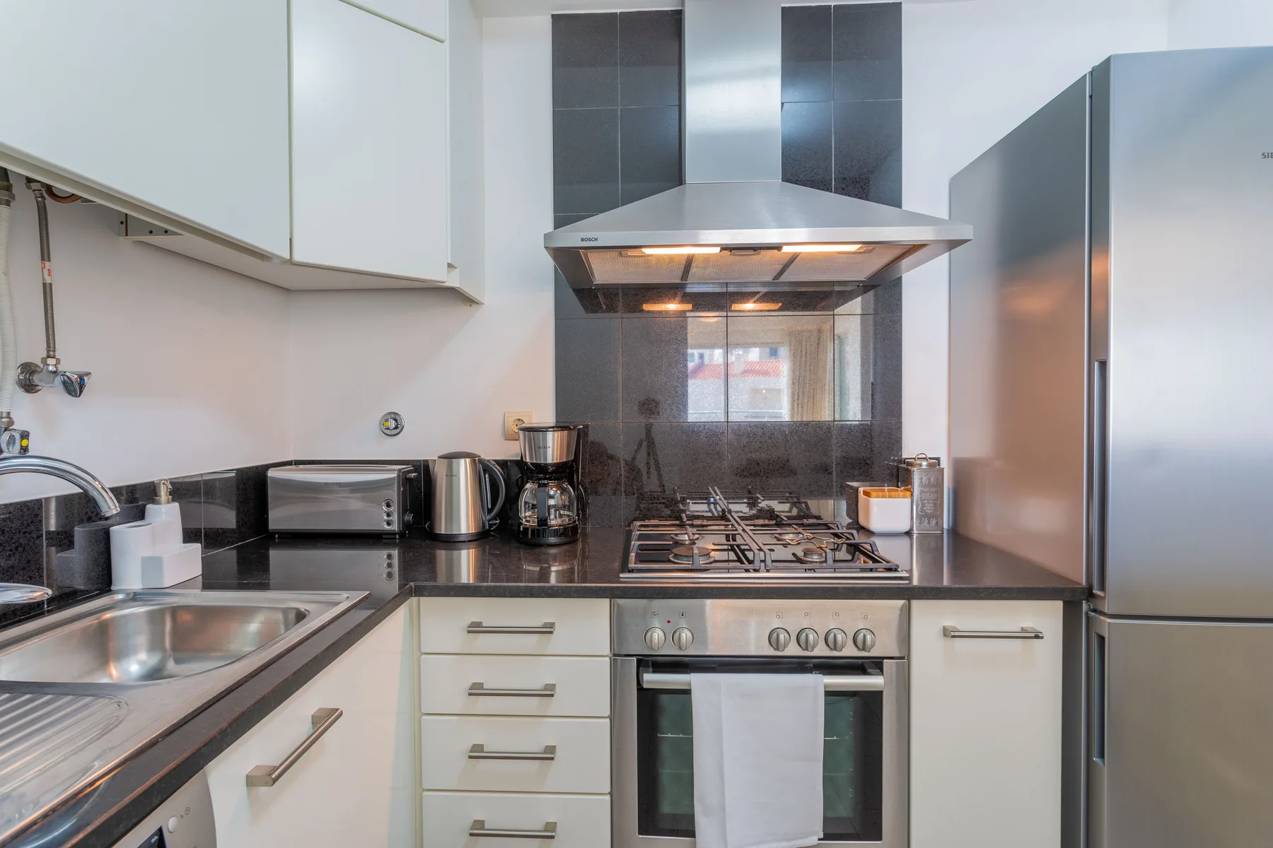 A modern kitchen with a sink, countertop appliances, and a stove.