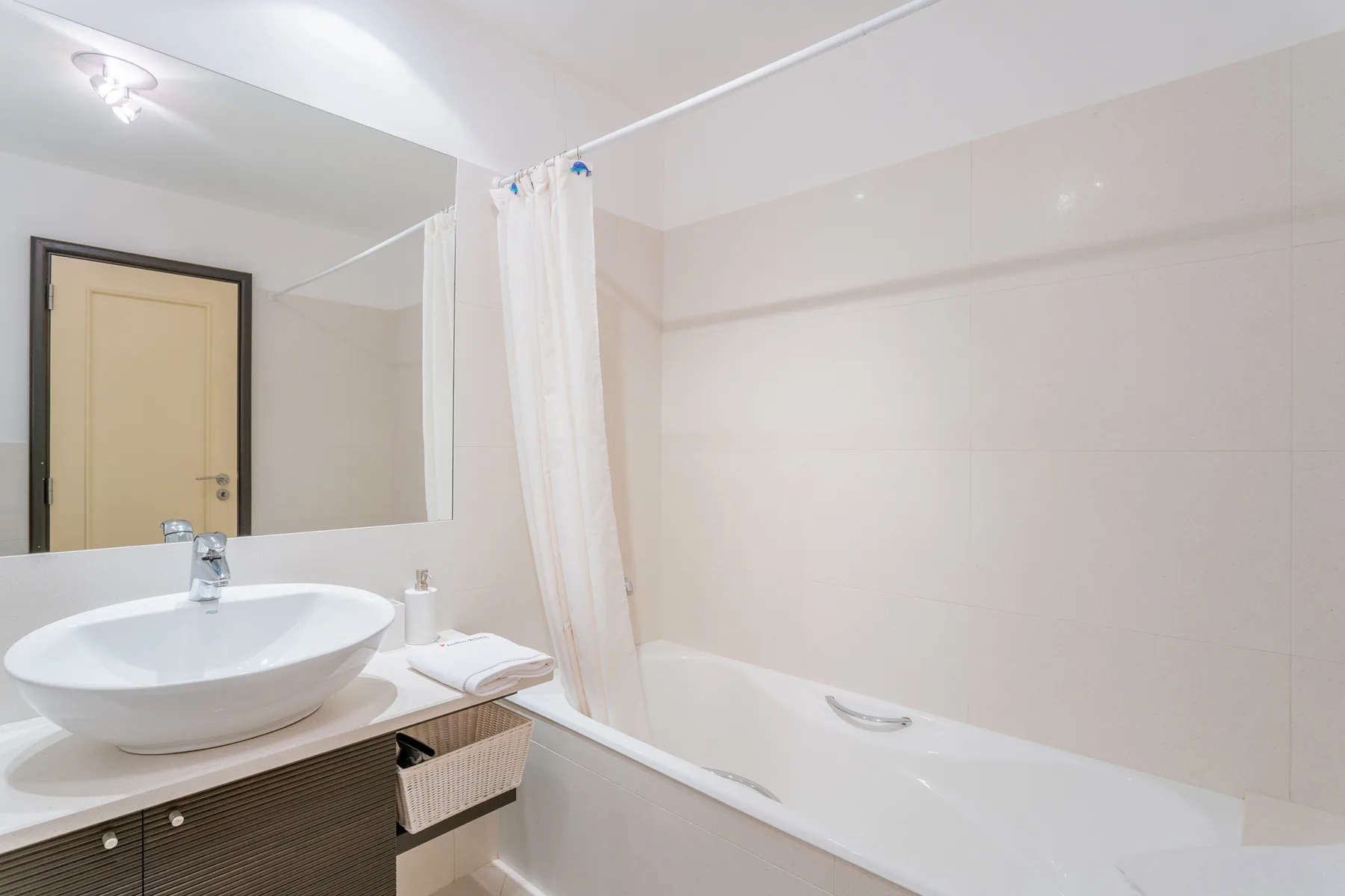 A bathroom with a sink, mirror, and bathtub behind a shower curtain.