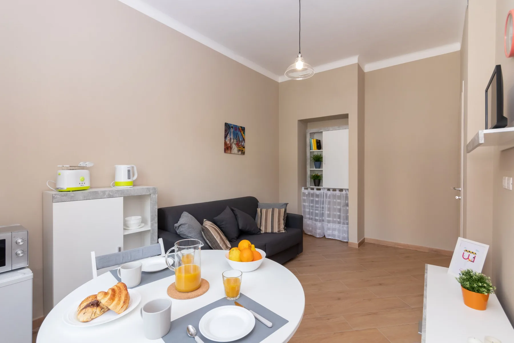 A living room with seating, a dining table, and a doorway to another space.
