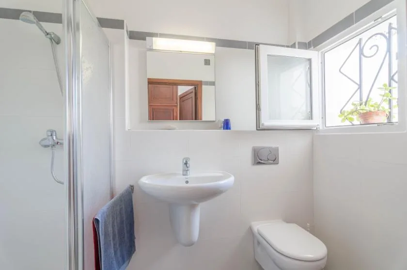 Un baño luminoso con lavabo, espejo y ducha.
