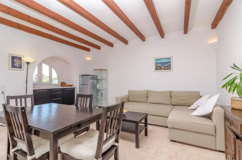 Una sala de estar y comedor con un sofá seccional beige y una mesa de comedor oscura.