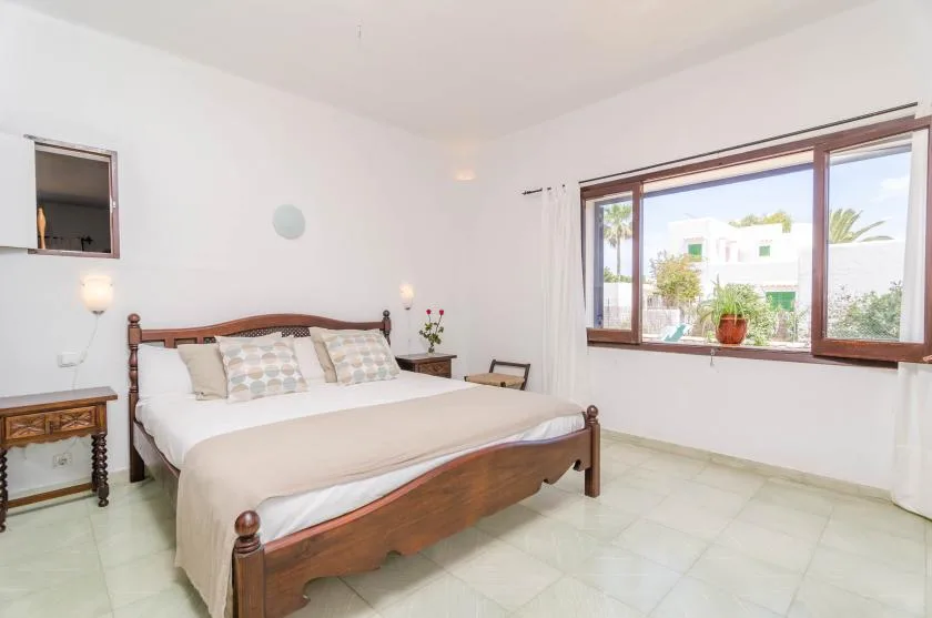 Un dormitorio con una cama de madera y una gran ventana con vistas a la vegetación.