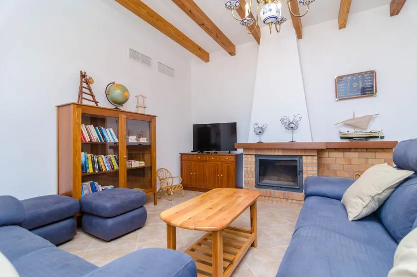 Sala de estar con asientos azules, una chimenea y una mesa de centro de madera.