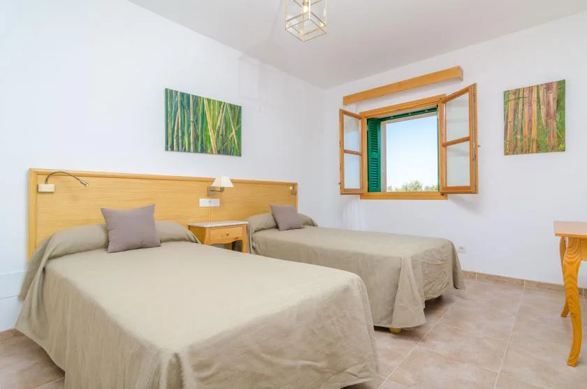 Un dormitorio con dos camas, un cabecero de madera y una ventana abierta.