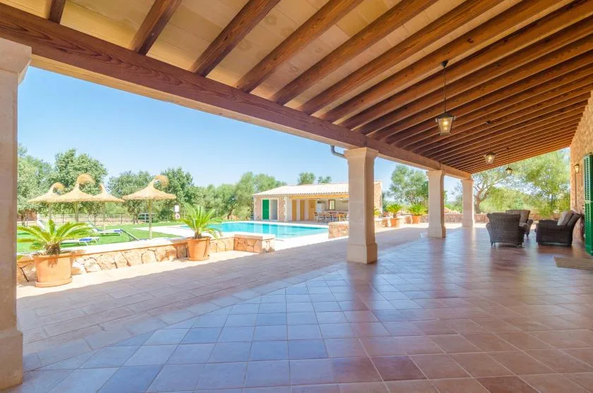 Un patio cubierto da a una piscina y a jardines.
