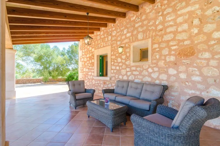 Un patio cubierto de piedra tiene asientos acolchados y suelo de baldosas.