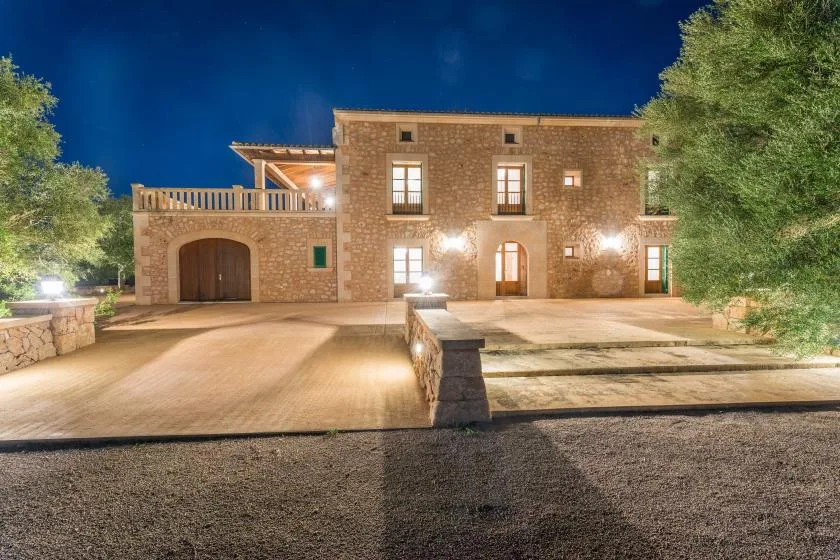 Un edificio de piedra se alza junto a un patio pavimentado bajo el cielo nocturno.