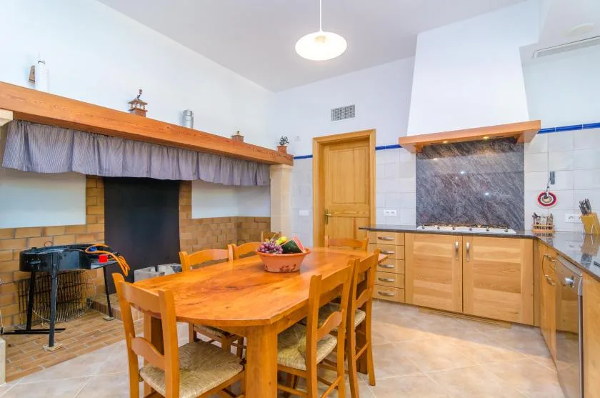 Una mesa de comedor está en una cocina junto a una encimera con frentes de madera.