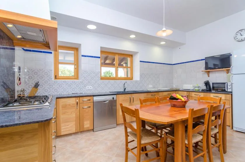 Una cocina luminosa con armarios de madera y una mesa de comedor rodeada de sillas.
