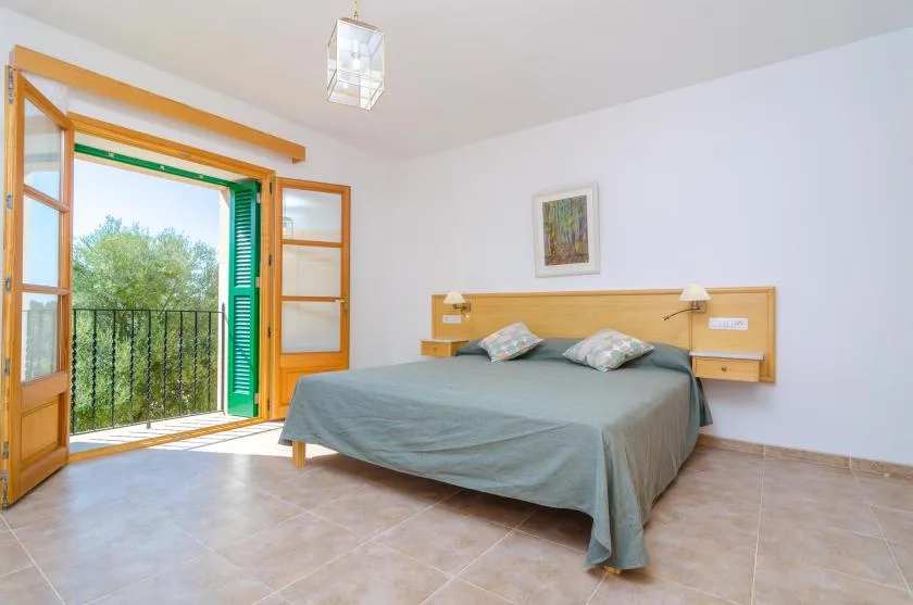 Un dormitorio con una cama doble junto a las puertas abiertas del balcón.