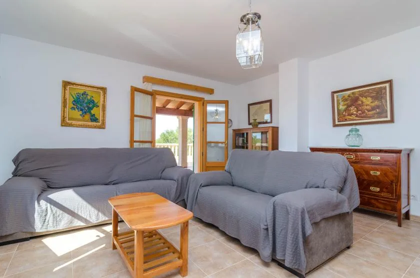 Una sala de estar con asientos grises, una mesa de centro de madera y una puerta abierta.