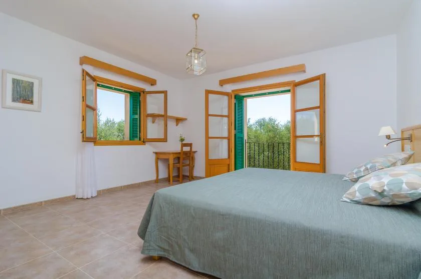 Un dormitorio con una cama junto a ventanas abiertas con vistas a la vegetación.