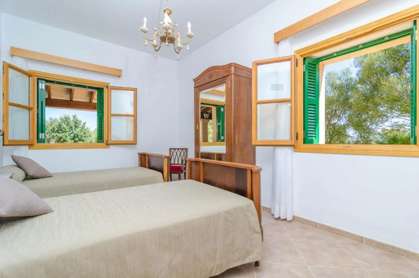 Un dormitorio con una cama, muebles de madera y ventanas abiertas.