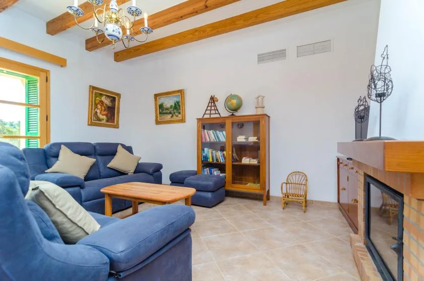 Una sala de estar con asientos azules, una mesa de centro de madera y una chimenea.