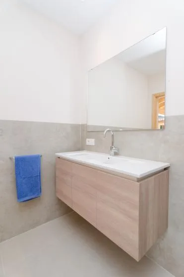 Un tocador de baño con lavabo está bajo un espejo grande.