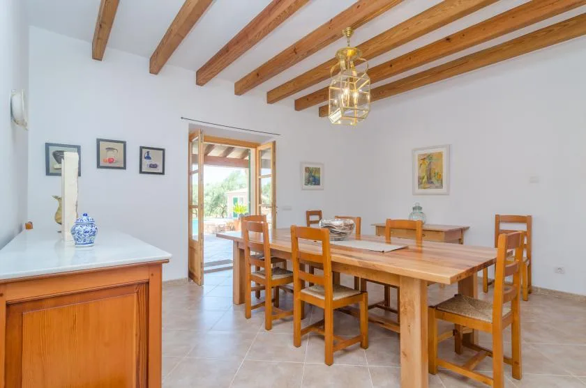 Comedor con una larga mesa de madera bajo vigas de techo expuestas.