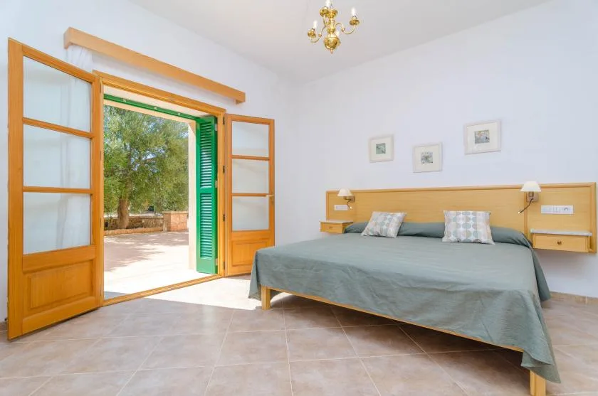 Un dormitorio con una cama grande junto a puertas abiertas hacia el exterior.