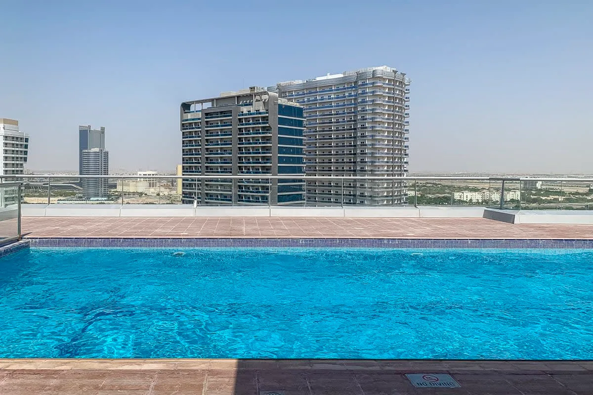 Una piscina en la azotea ofrece vistas de edificios modernos bajo un cielo despejado.