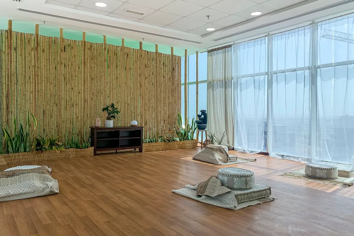 Una sala luminosa de descanso con cojines en el suelo y cortinas translúcidas junto a las ventanas.