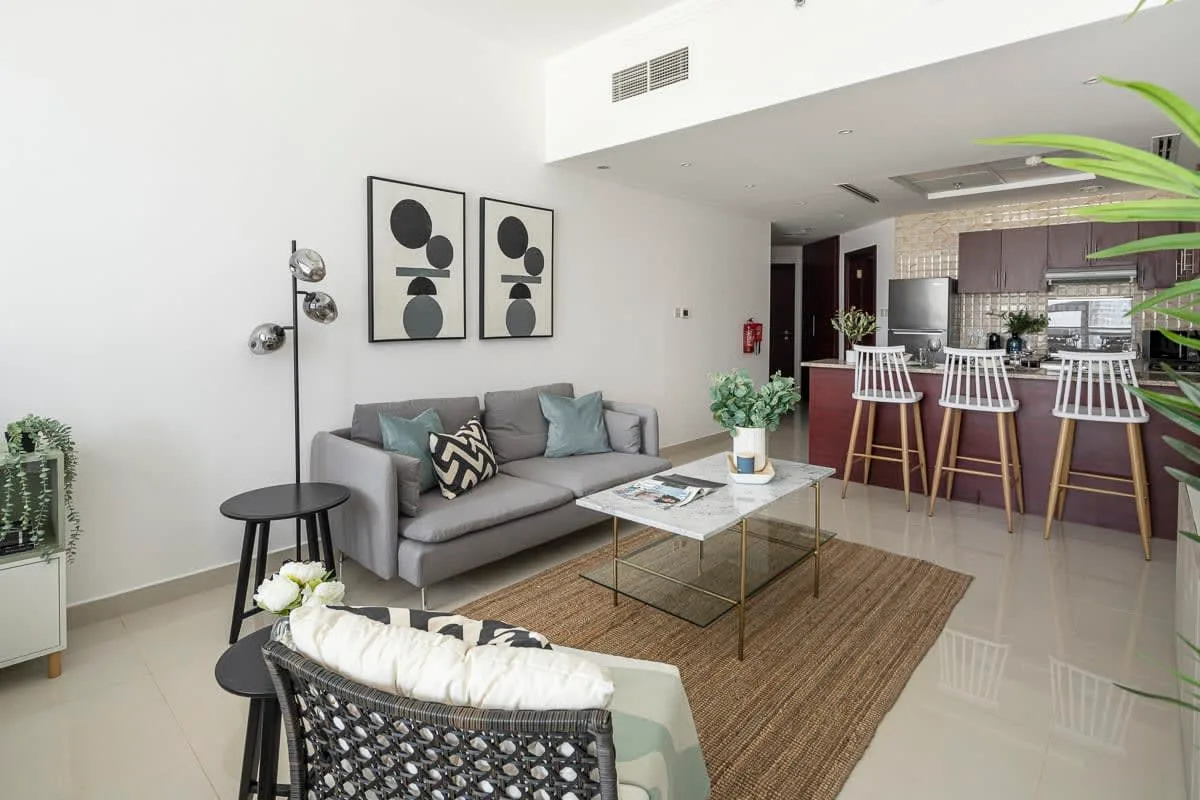 Sala de estar de estudio con asientos, mesa de centro y cocina abierta.