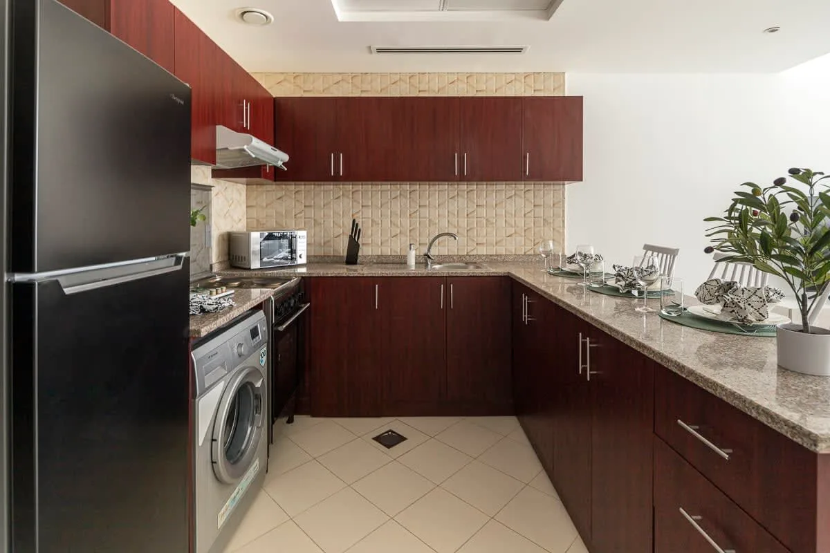 Una cocina moderna con gabinetes de madera oscura, una encimera y una lavadora.