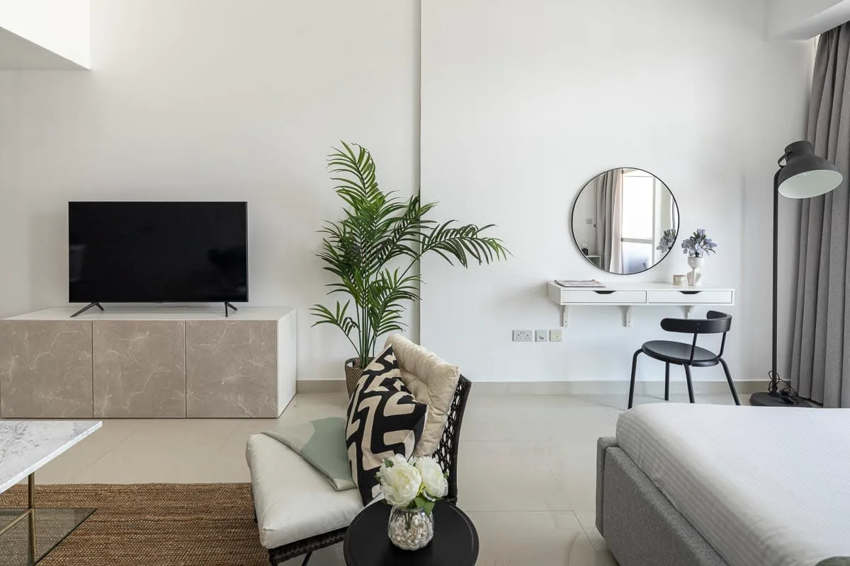 Una sala de estar luminosa con televisor, asientos y una planta en maceta.