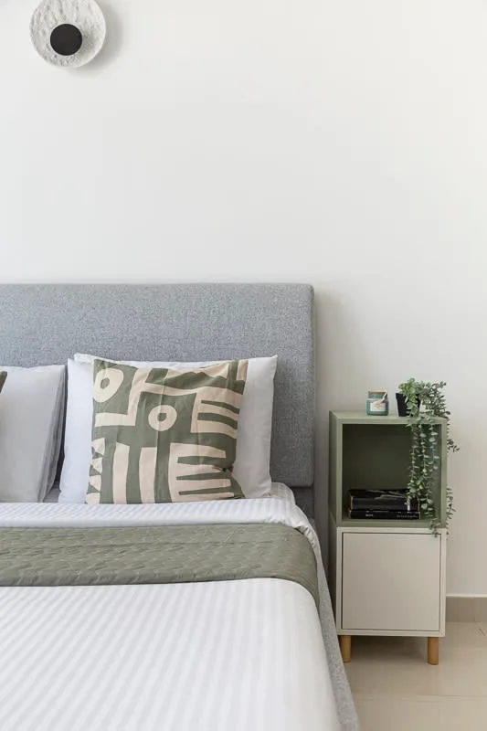 Un dormitorio con una cama ordenada y un pequeño mueble junto a ella.