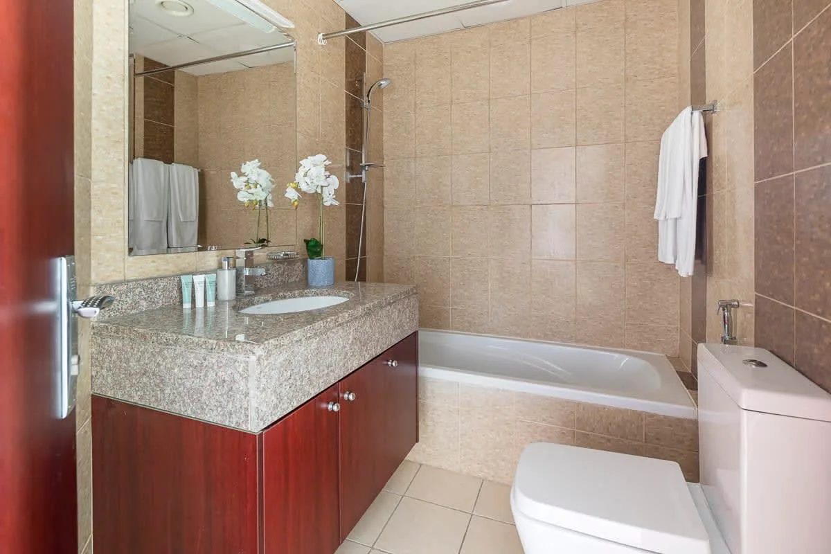Un baño con azulejos, bañera, lavabo con mueble e inodoro.