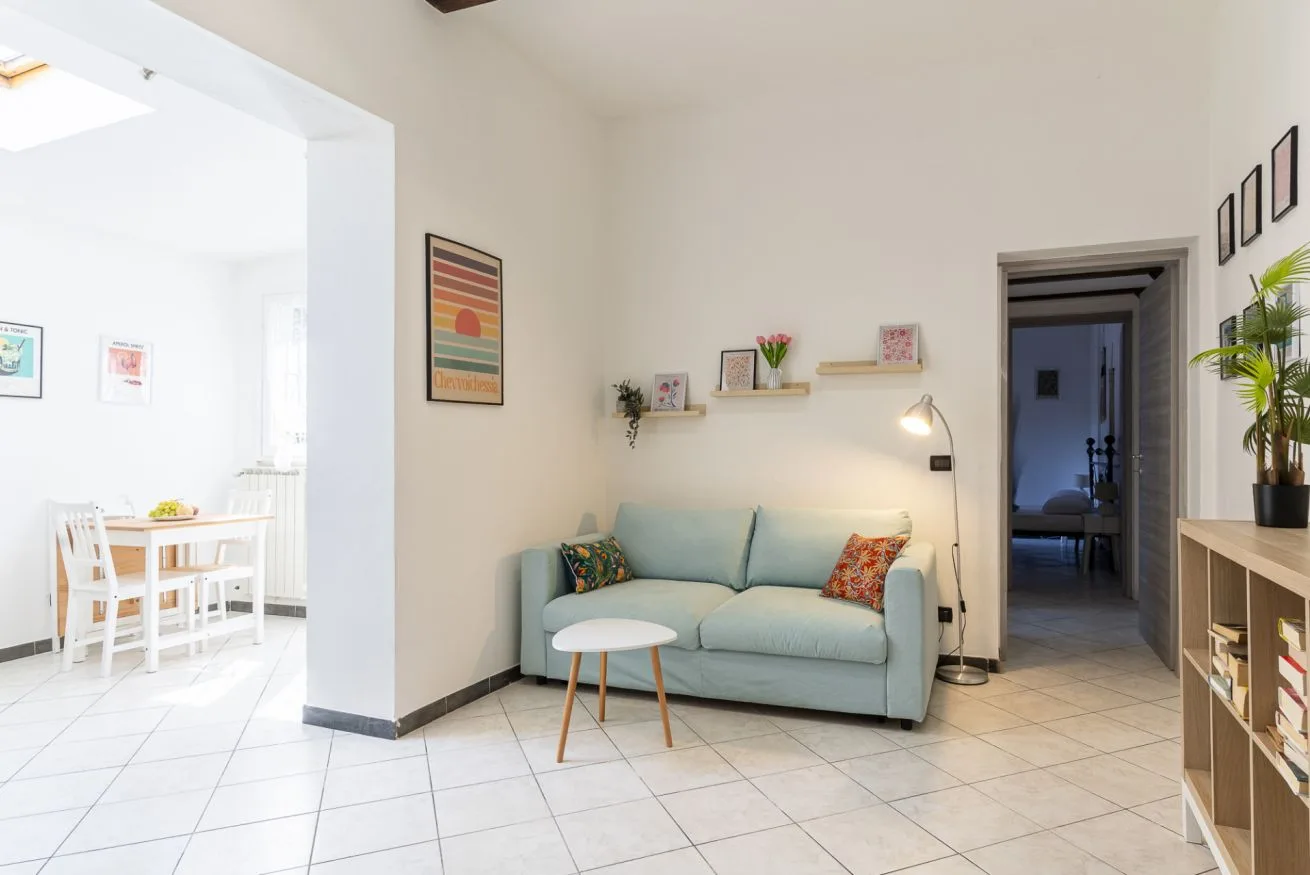 A bright living area with a pale blue sofa, small table, and open dining space.