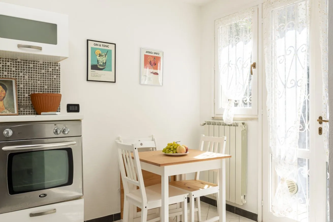 A bright kitchen dining area with a small table beside a glass door.