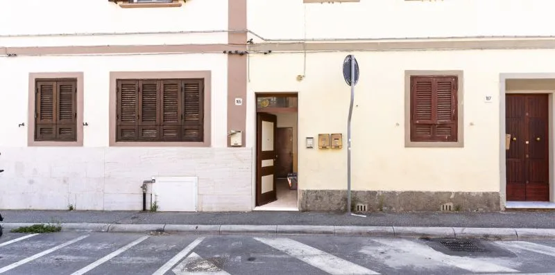 Street-facing building facade with shuttered windows, doorways, and a signpost beside the road.