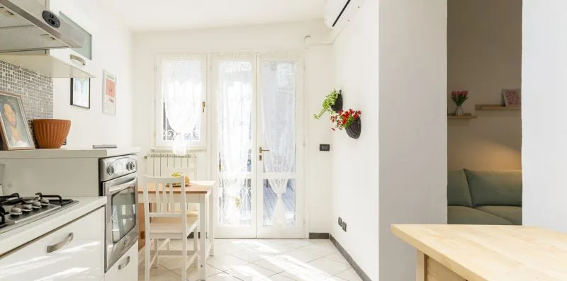 A bright kitchen and dining area with a table beside tall windows.