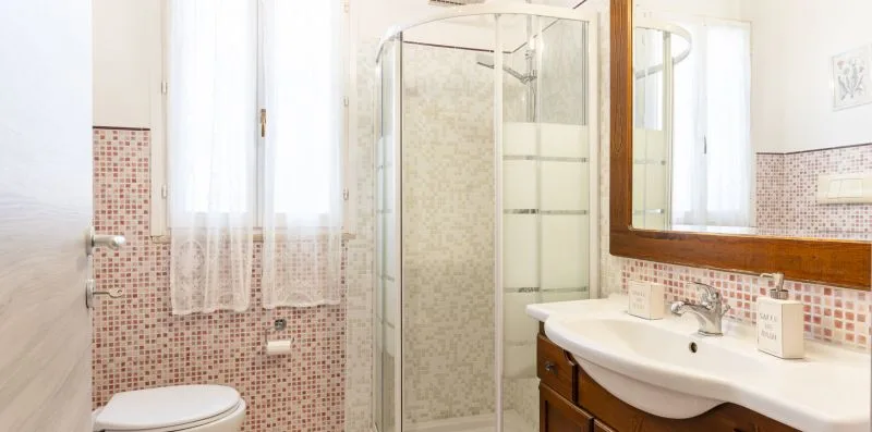 A bright bathroom with a glass shower, sink, and large wall mirror.