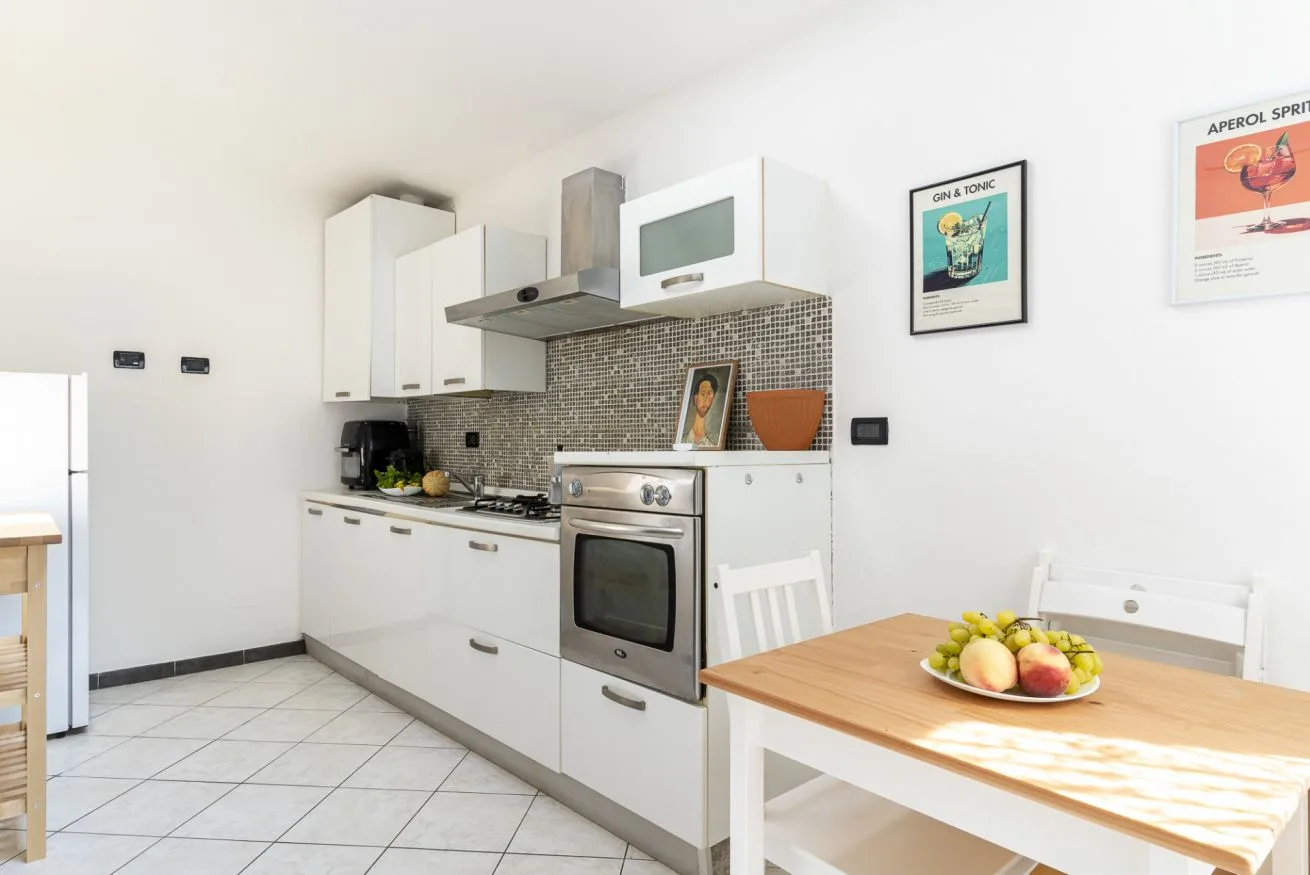 A bright kitchen with white cabinets, cooking appliances, and a dining table.