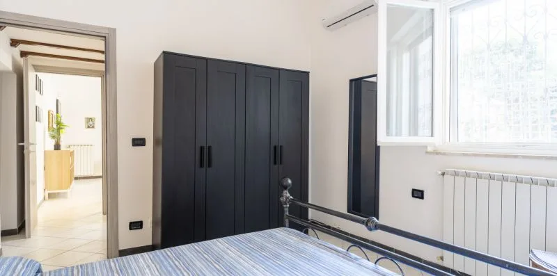 A bedroom with a dark wardrobe and a large window.