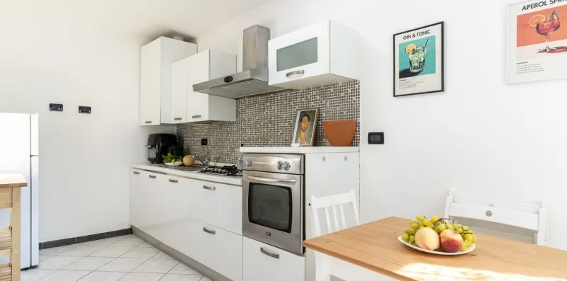 A bright kitchen with white cabinets, a stove, and a dining table.