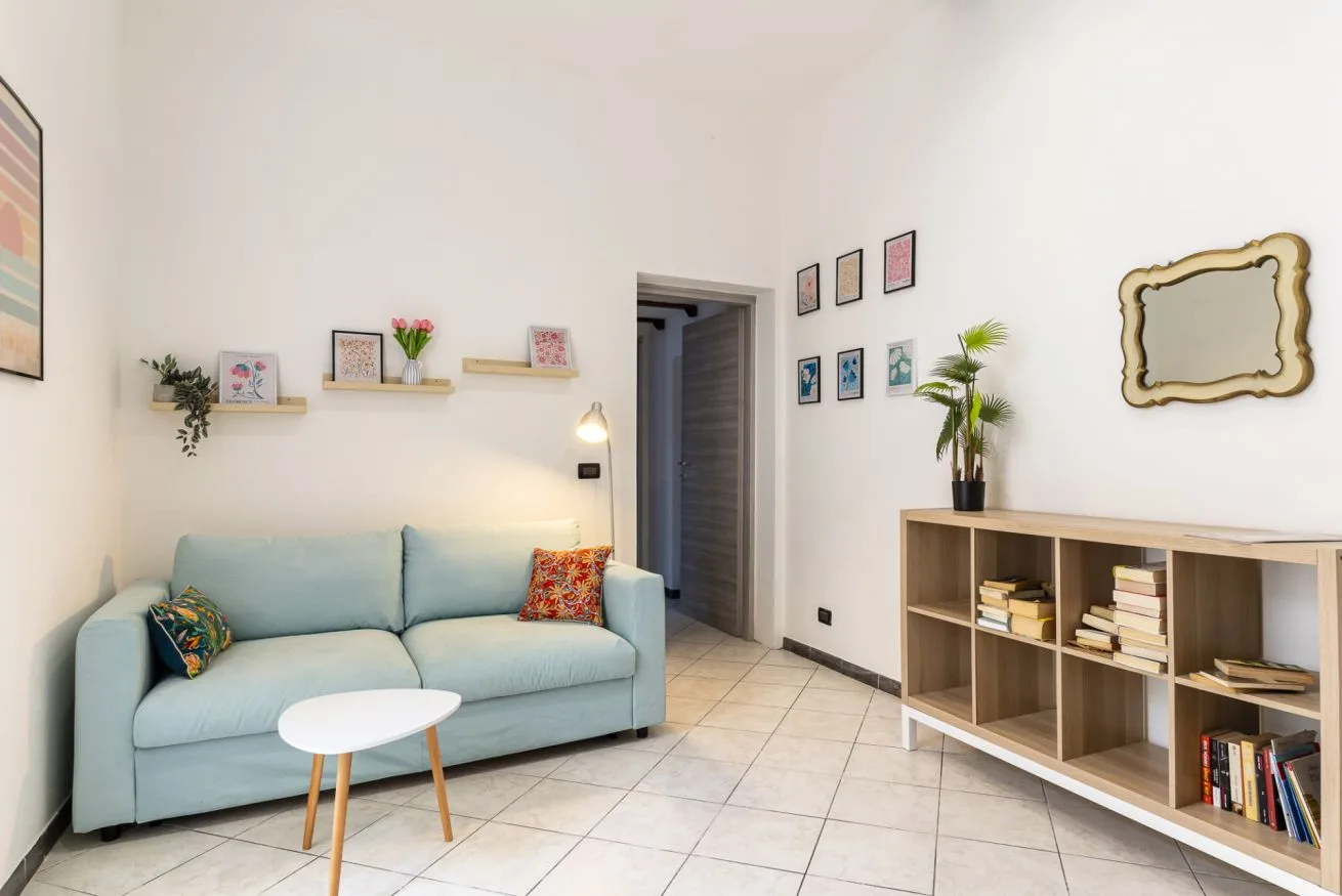 A bright living room with pale blue seating and a low wooden shelving unit.
