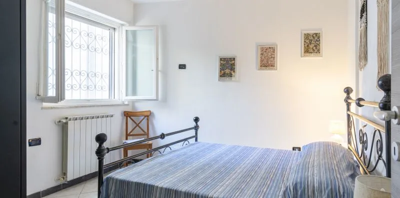A bedroom with a bed beside a window and radiator.