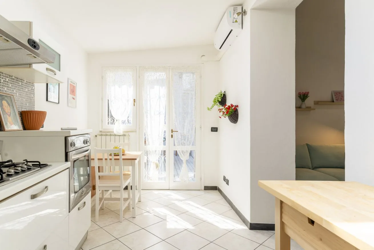 A bright kitchen and dining area opens onto a balcony through glass doors.