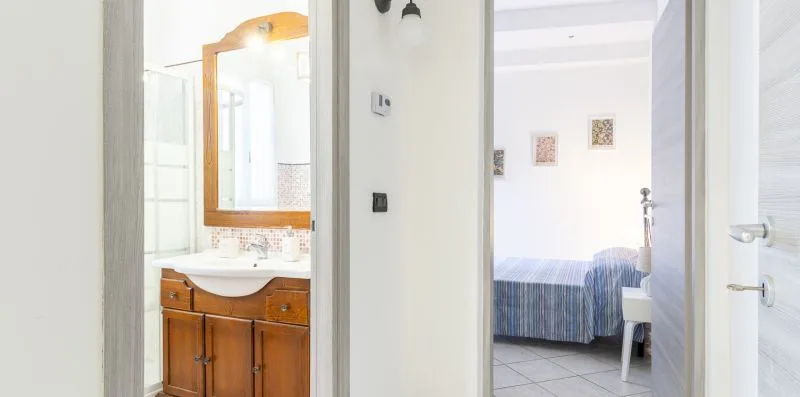 A bathroom vanity and an adjoining bedroom are visible through open doorways.
