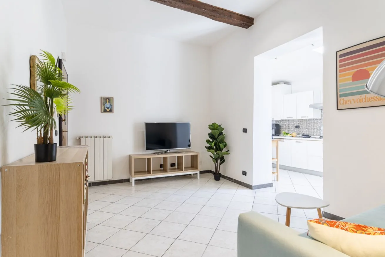 A bright living room with a television and an open doorway to the kitchen.