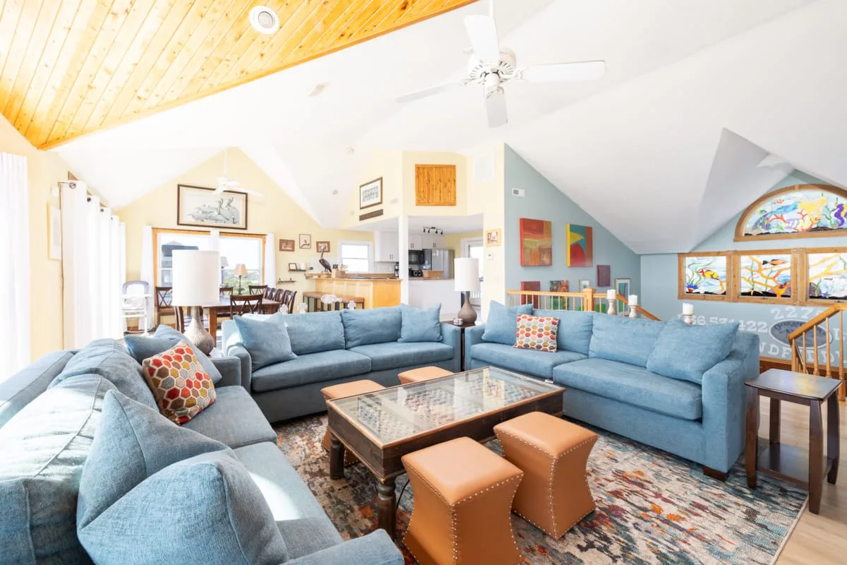 A spacious living room with blue seating and a dining area in the background.