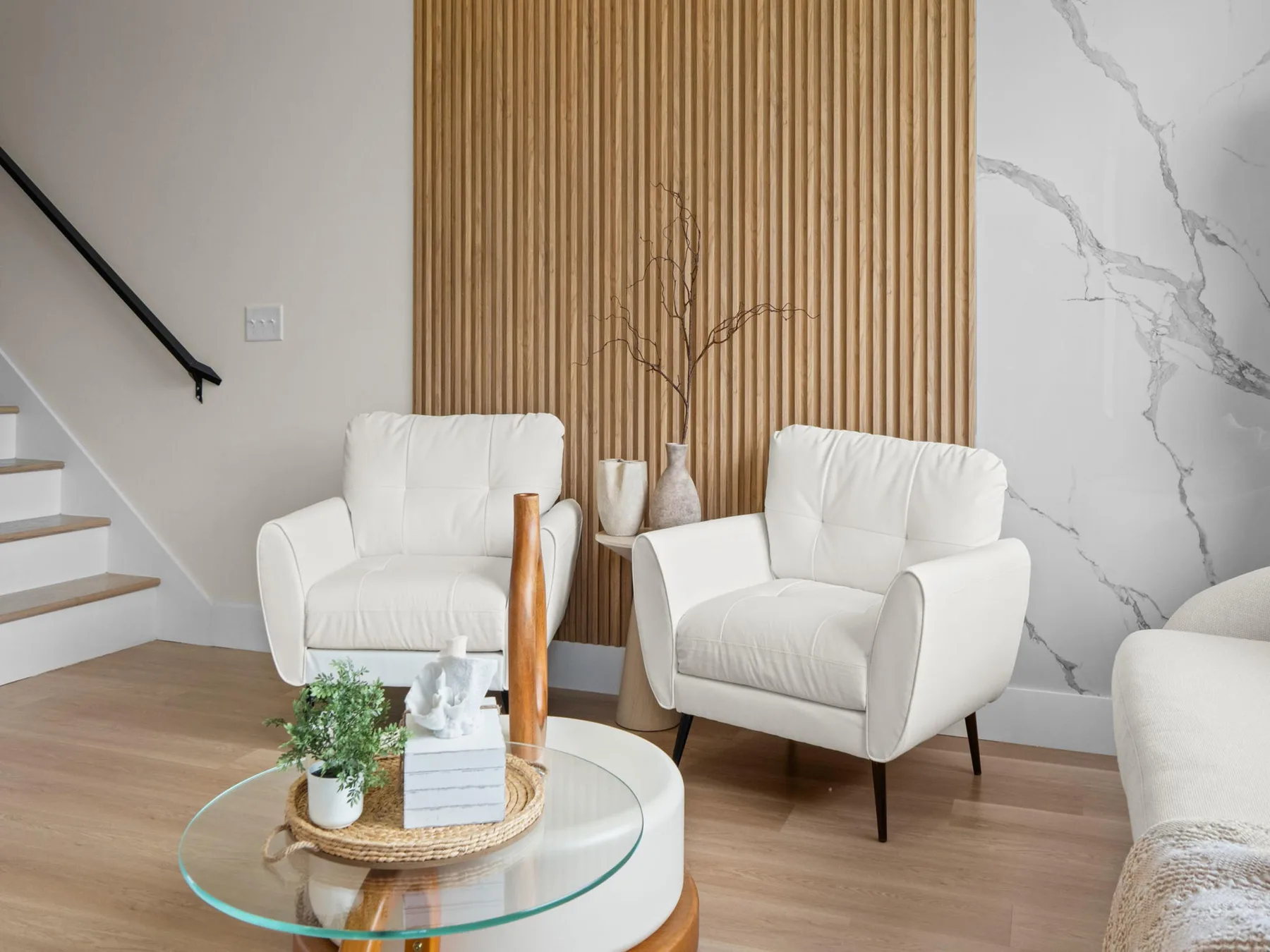 Una sala luminosa con asientos blancos alrededor de una mesa de centro redonda de vidrio.