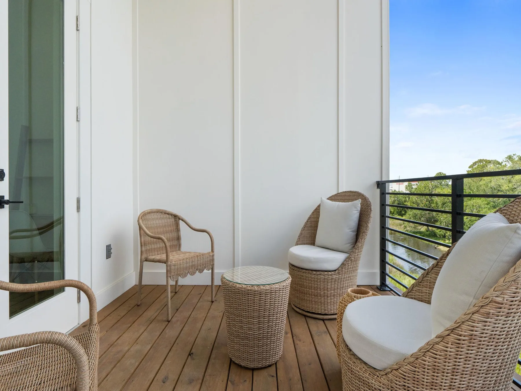 A balcony seating area with wicker chairs and a view of the trees.