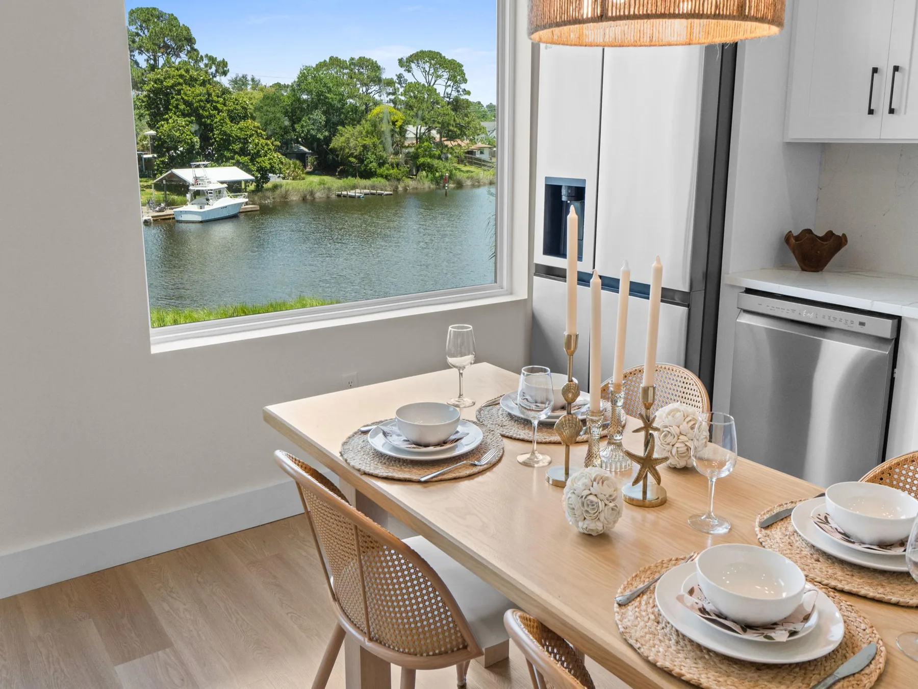 Una mesa de comedor está puesta junto a una ventana grande con vistas a un canal.