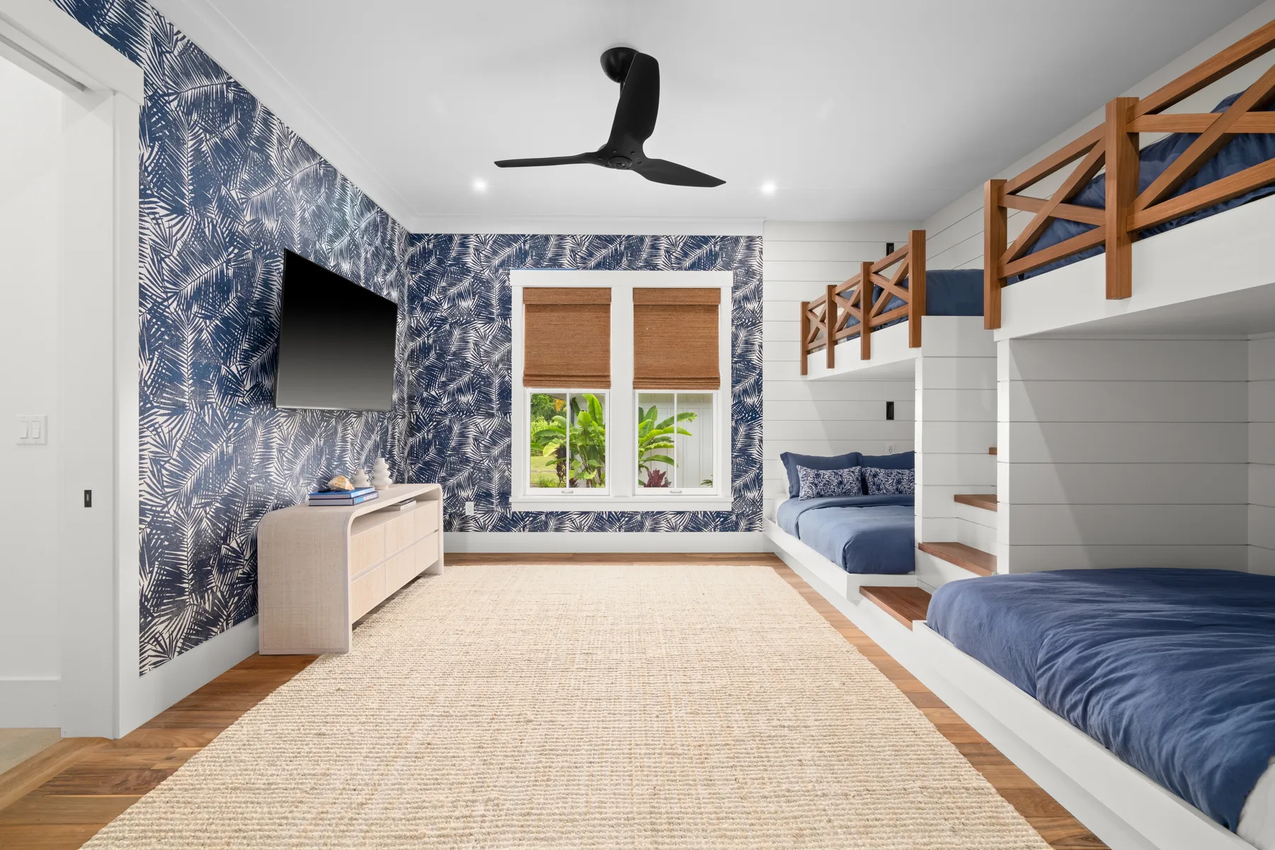 A bright bedroom with blue patterned walls and built-in beds.