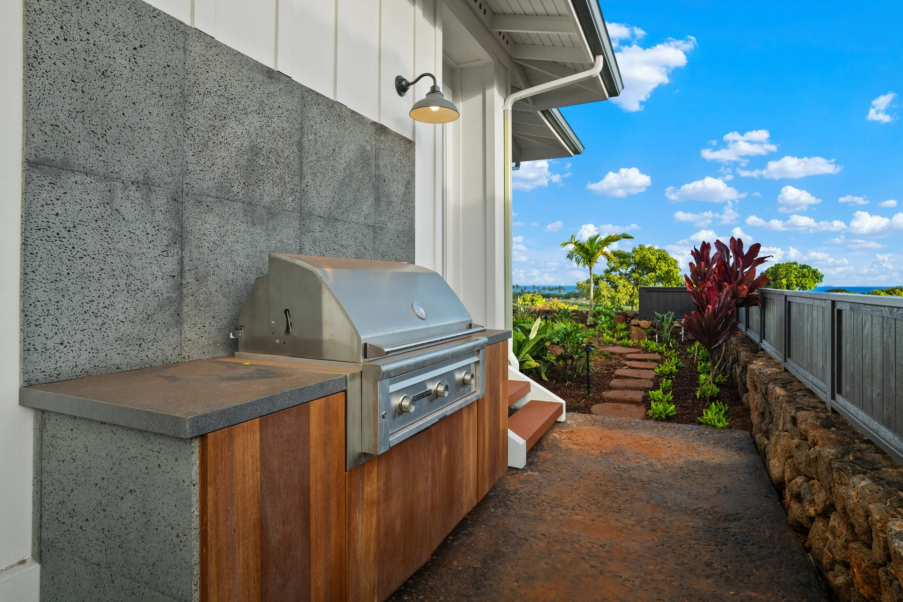 An outdoor cooking area beside a garden path and railing.