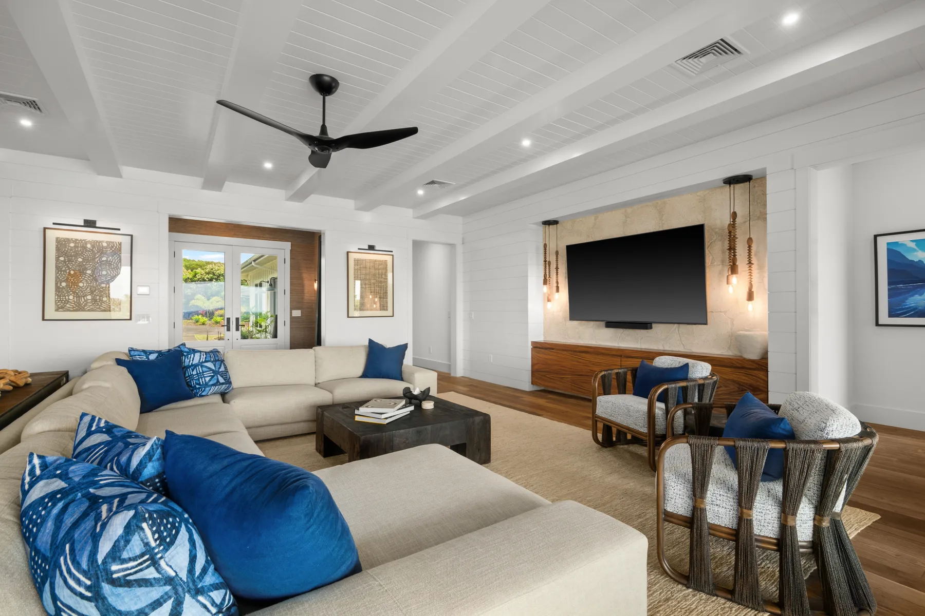 A bright living room with sectional seating, blue cushions, and a television on the far wall.