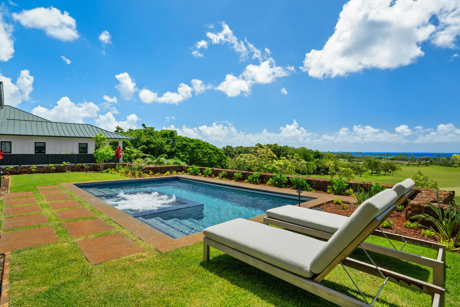 An outdoor swimming pool and lounge seating sit amid landscaped gardens.